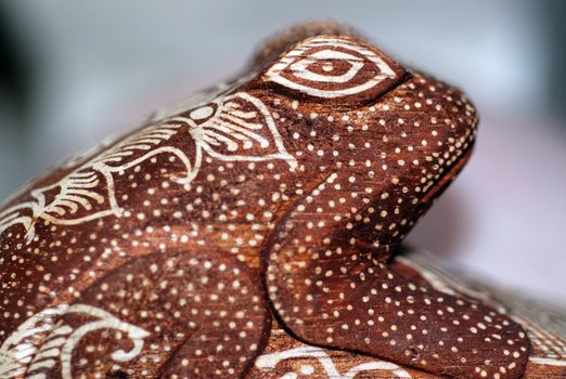 A close-up of a carved wooden frog doorstop