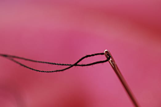 A close-up of a threaded needle, ready to sew.