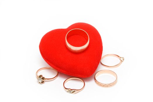 Five gold rings lay near to red velvet heart