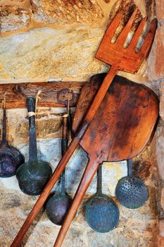 Picture of traditional oven and cooking utensils arranged against a stone wall