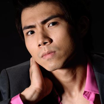 Cool Asian young businessman, closeup portrait against black.