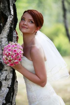 The beautiful bride with bouquet in park