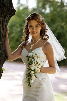 The beautiful bride with bouquet in park