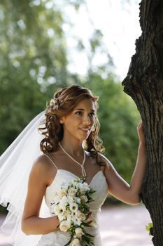 The beautiful bride with bouquet in park