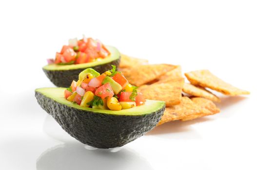 Delicious salsa served in an avocado half with chips.