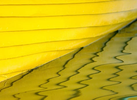 Old yellow wooden boat reflected in the water