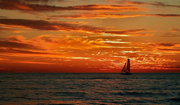 Sailboat against a brilliant red and yellow sunset