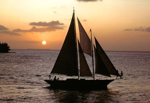 People enjoying a sail boat just at sunset