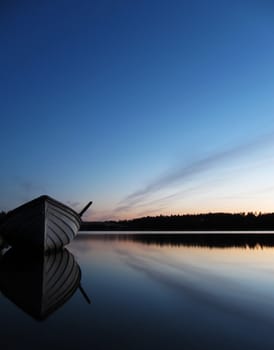 Wooden boat at dusk on a very blue lake                               