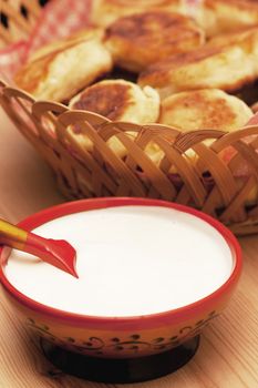 Curd pancakes and sour cream on a wood table