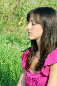 young brunette woman portrait outdoor over green grass