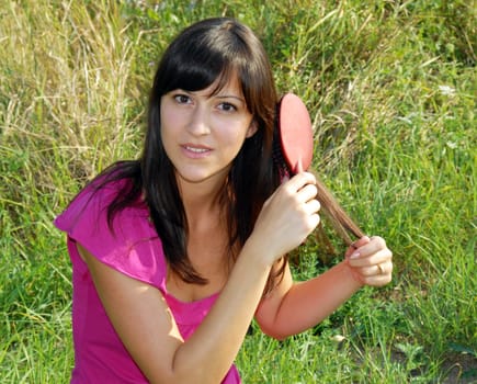 young brunette woman portrait outdoor brushing her hair