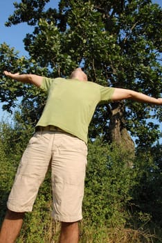 man with spreading hands standing outdoor over natural background