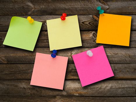 Multicolored stickers and notes and drawing pins at the wooden background