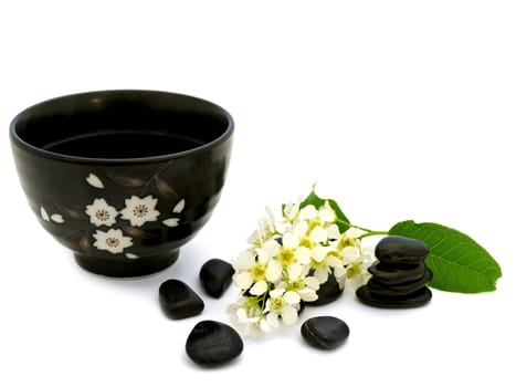 tea bowl near the spa stones and flower over white background 