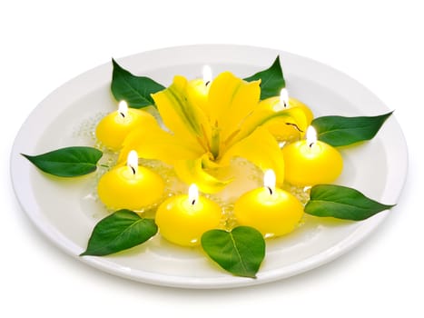 floral spa decoration with lily, candles and green leaves over white background 