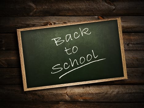 School blackboard at abstract dark wooden background  