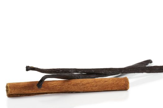 cinnamon stick and two vanilla beans on white background