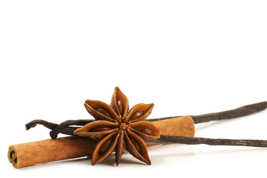 cinnamon stick, star anise and two vanilla beans on white background