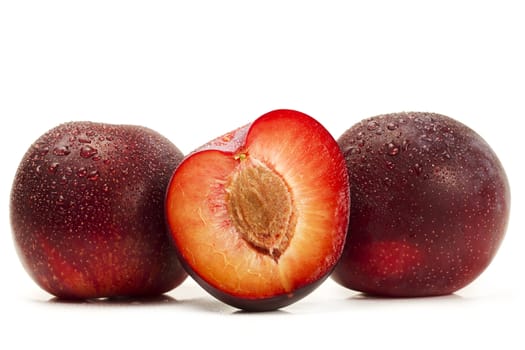 two and a half wet plums on white background