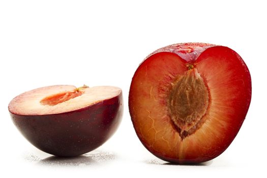 two half wet plums on white background