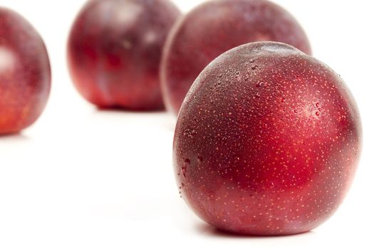 wet plum in front of others on white background