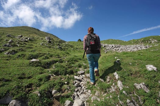 Photo of an active female with backpack hiking up a mountain trail. Slight motion blur on hiker.