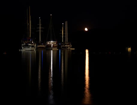 Boats at night with a moon on the dark background