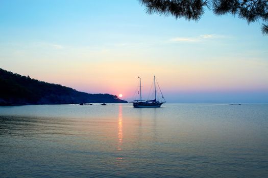 A beautiful Mediterranian sea sunrise with alone ship in the foreground.