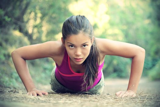 Exercise woman doing push-ups outdoors in the forest, Beautiful young female athlete. 