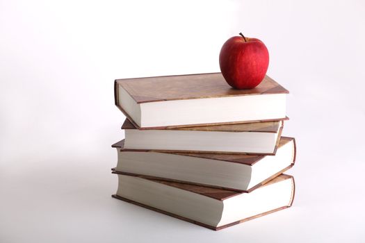 Red apple on the stack of the books on white background