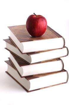 Red apple on the stack of the books on white background