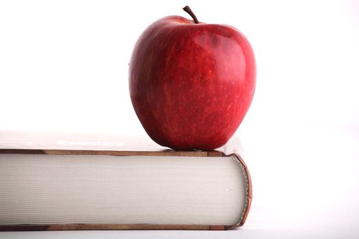 Red apple on the big book on white background