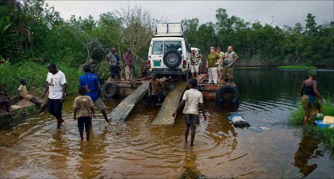 Crossing on a raft. Through wild small river in Africa (Congo) people and cars are forwarded on a raft.