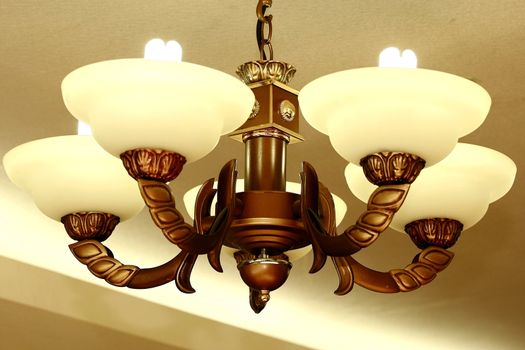 lighted chandelier pictured against a ceiling with light as background