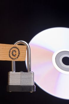 Copyright symbol on a piece of wood attached to a lock next to a CD.