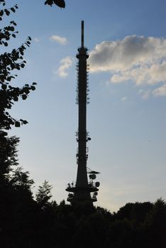 communication tower with trees and clouds in a sky