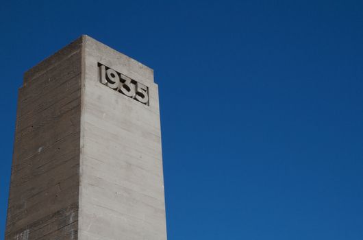 Deco concrete tower with 1935 engraved against a dark blue sky