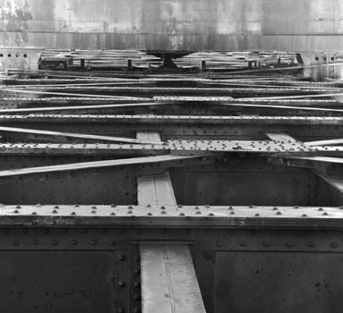 Framework of old steel beams and girders with backdrop of concrete wall