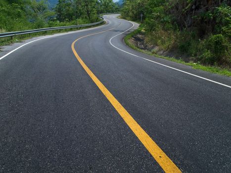 The road curves up the mountain. Line yellow and white road.