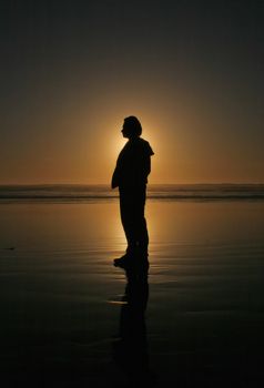 silhouette of the man at the Pacific ocean beach at sunset