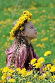 Nice, young girl enjoy summer time in the dandelion meadow.