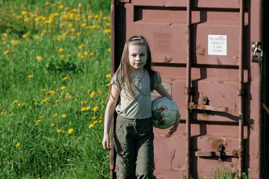 Nice, young girl with ball enjoy summer time in the dandelion meadow.