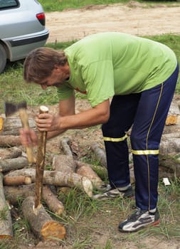 The man cuts a wooden peg on wooden logs