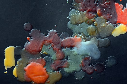 Abstract background made from colored wax drops on black paper