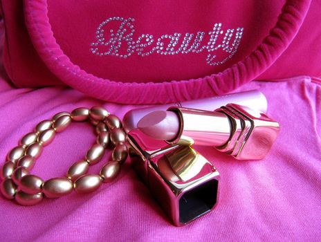 A lipstick, perfume vaporizer, two fashion bracelets and a pink cosmetics bag in gold and pink.