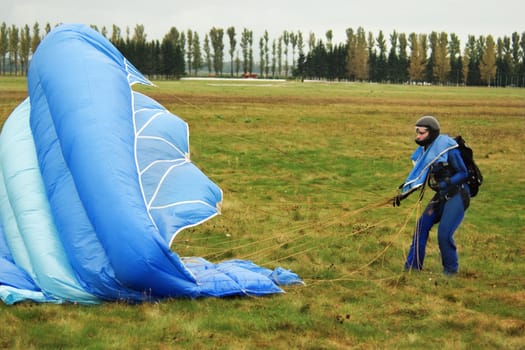 The girl in dark blue overalls with parachute on airfield