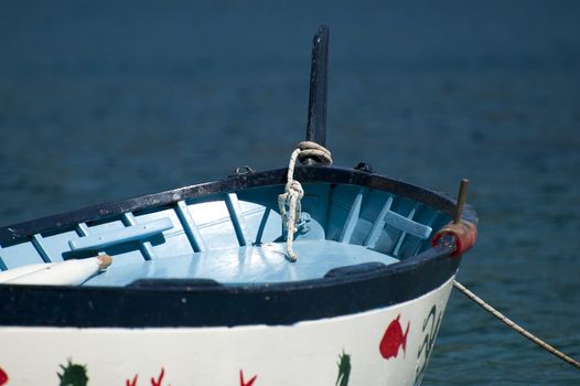 An old colored rowboat anchored in the sea