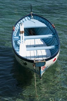 An old colored rowboat anchored in the sea