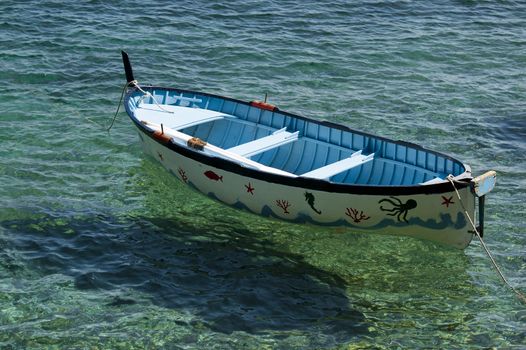 An old colored rowboat anchored in the sea